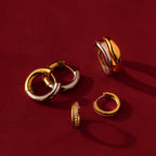 Half Pave Huggies in 18K Gold shine against a rich red background.