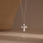 The Art Deco Cross Necklace, a silver chain necklace with a cross-shaped pendant, is showcased against a soft, neutral background.