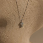 The Mother of Pearl Cross Necklace in Silver features an iridescent inlay pendant and is displayed on a textured beige mannequin bust—a timeless piece that brings elegance to any style.