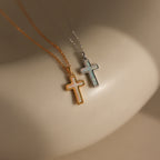 Two Mother of Pearl Cross Necklaces, one with a gold chain and one with a silver chain, featuring iridescent inlays, are displayed on a smooth, light surface—a stunning showcase of timeless jewelry.