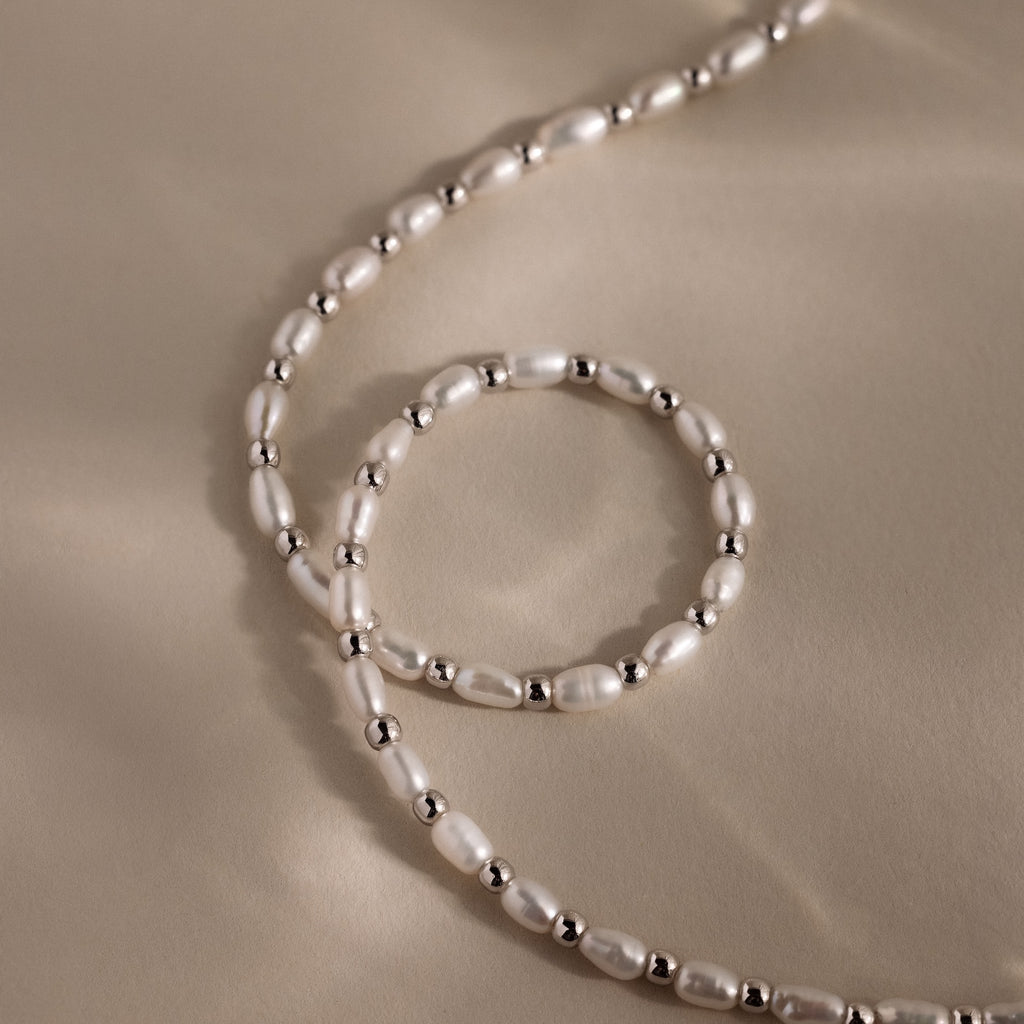 The Beaded Pearl Necklace in White Gold features alternating freshwater pearls and polished beads, displayed on a beige background.