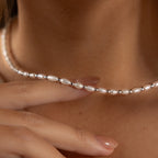 A hand touches the Beaded Pearl Necklace, adorned with freshwater pearls and delicate polished beads that rest gracefully on a neck.