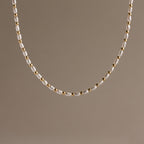 The Beaded Pearl Necklace in 18K Gold showcases alternating small freshwater pearls and polished gold beads, set against a plain beige background.