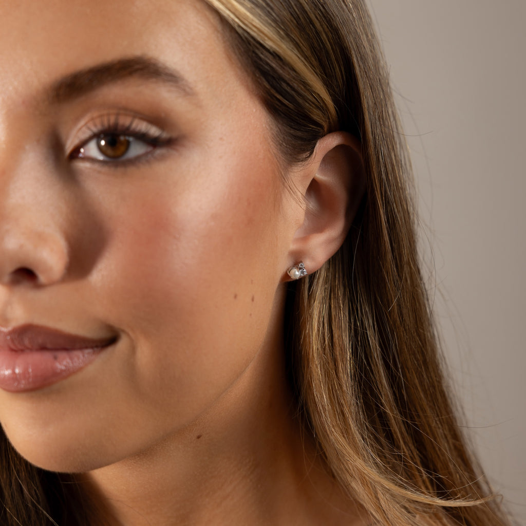 Close-up of a woman with long hair softly smiling, wearing elegant Pearl Diamond Cluster Studs in Sterling Silver.