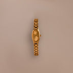 The Slim Oval Timepiece gold wristwatch with a polished link bracelet is shown against a plain beige background.