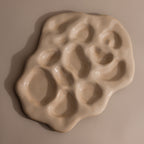 The Organic Treasure Trove Jewelry Dish is an irregular beige ceramic piece featuring multiple rounded indentations, ideal for displaying minimalist or organic jewelry against a neutral backdrop.