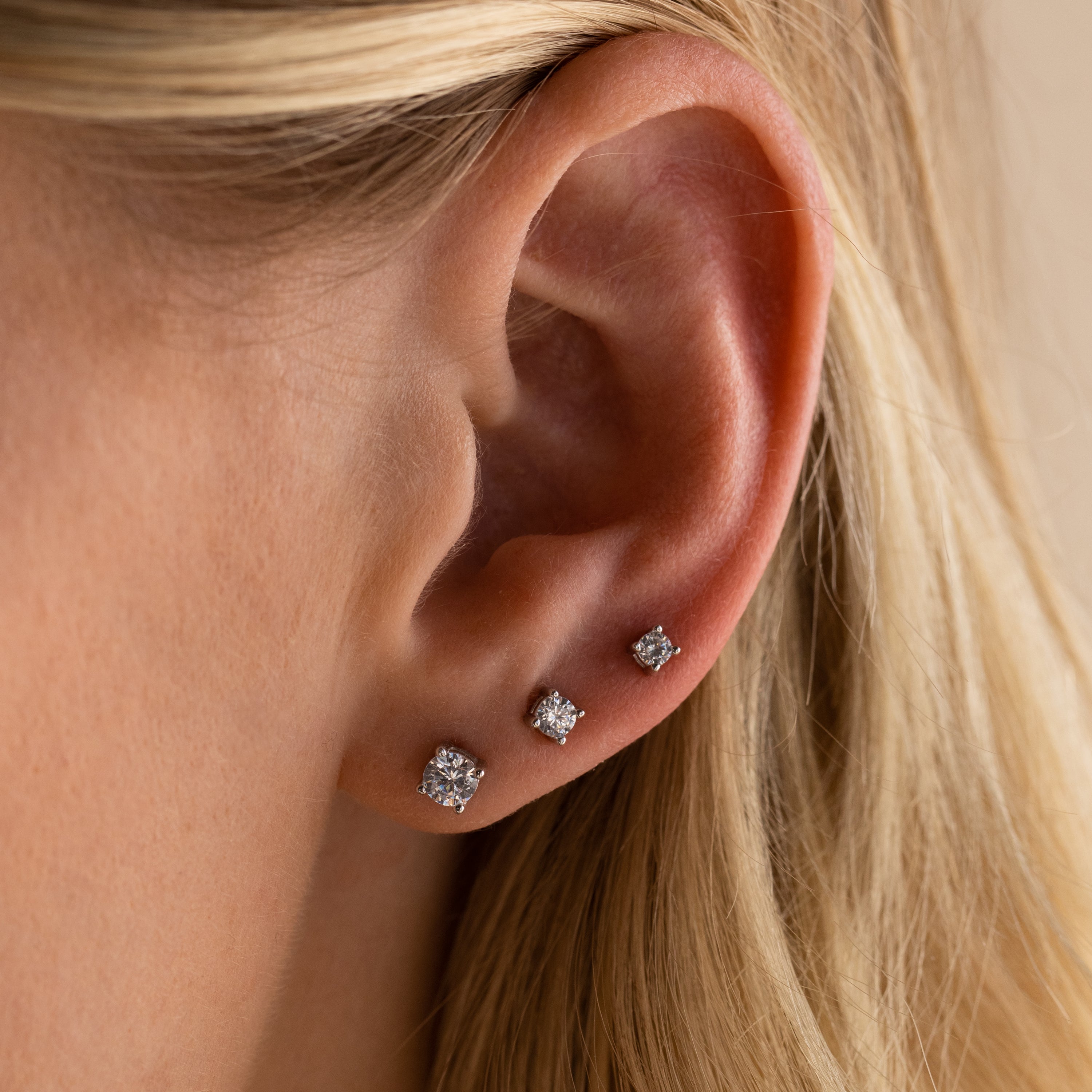 Close-up of a woman's ear adorned with the Booker Diamond Studs Set—three lightweight diamond studs perfect for everyday wear.