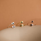 The Paw Print Duo Heart Ring, available in silver, gold, and rose gold with letter engraving, makes the perfect Pet Lovers Gift. These delicate heart rings rest elegantly on a beige surface.