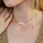 A woman wears an Old English Name Necklace with "Elizabeth" stylishly crafted in elegant script letters.