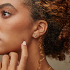 Woman with curly hair wearing a gold crescent moon earring accented with a star, touching her face gently—an elegant style that pairs perfectly with Aeon Studs or other constellation-inspired earrings.