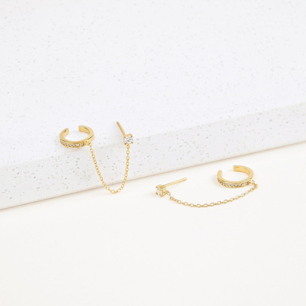 Pave Chain Ear Cuffs featuring delicate chains and sparkling crystals, showcased on a white textured surface.