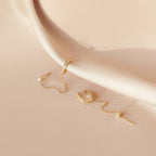 Pave Chain Ear Cuffs elegantly displayed on pale, silky fabric feature a delicate chain for a refined look.