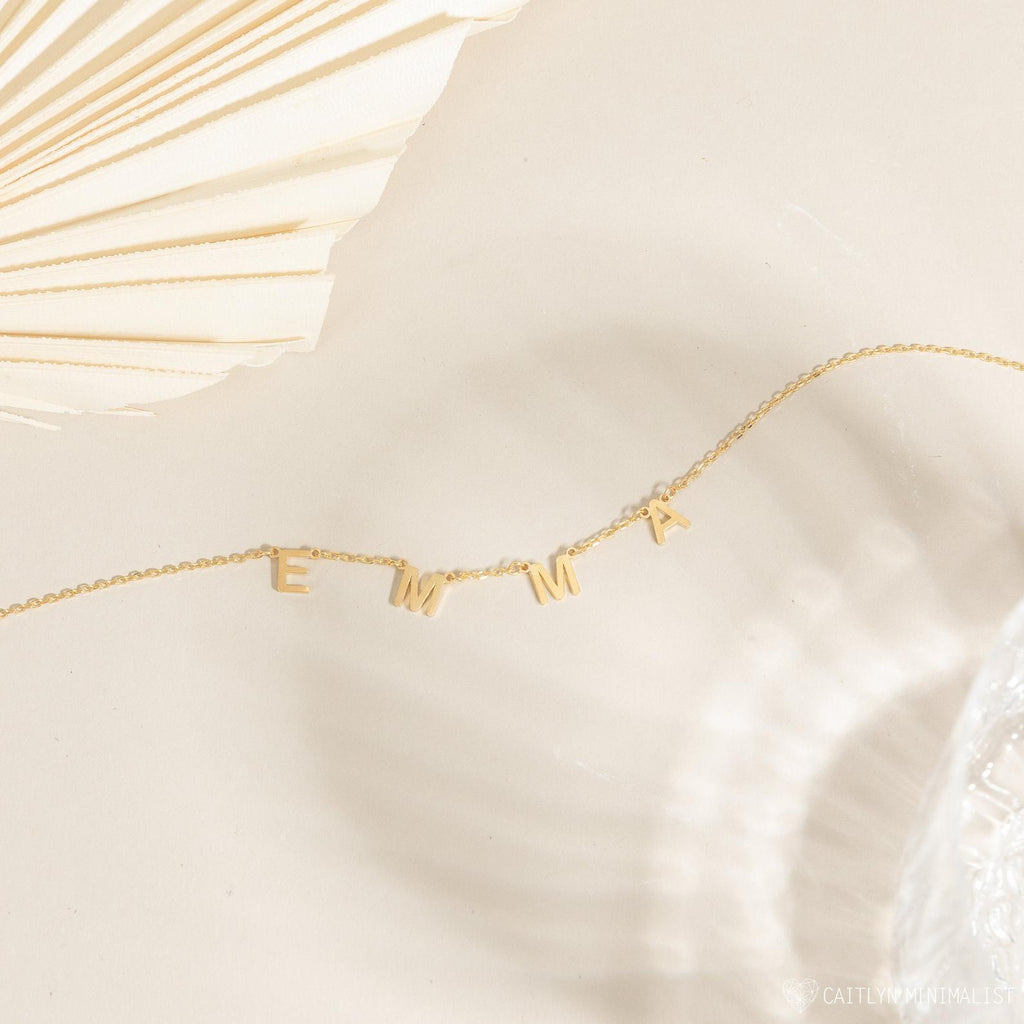 Custom Letter Necklace with gold charms spelling EMMA shown on a neutral background—an ideal personalized jewelry piece for any style.