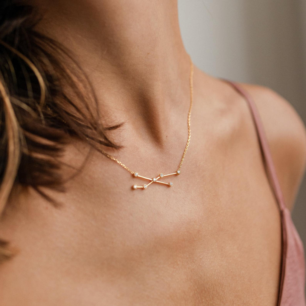 Close-up of a woman's neck wearing the gold Constellation Necklace paired with a pink spaghetti strap top.