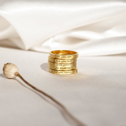 Four Ann Thin Message Rings engraved and stacked on white fabric, paired with a dried plant stem in soft natural light—a timeless personalized set, perfect as a thoughtful holiday gift.