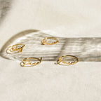 Four delicate Venice Name Rings with cursive words rest on a light surface, casting soft shadows—a beautiful touch of custom jewelry.