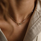A close-up shows someone wearing the gold Interlocking Circles Necklace with a beige collared shirt.