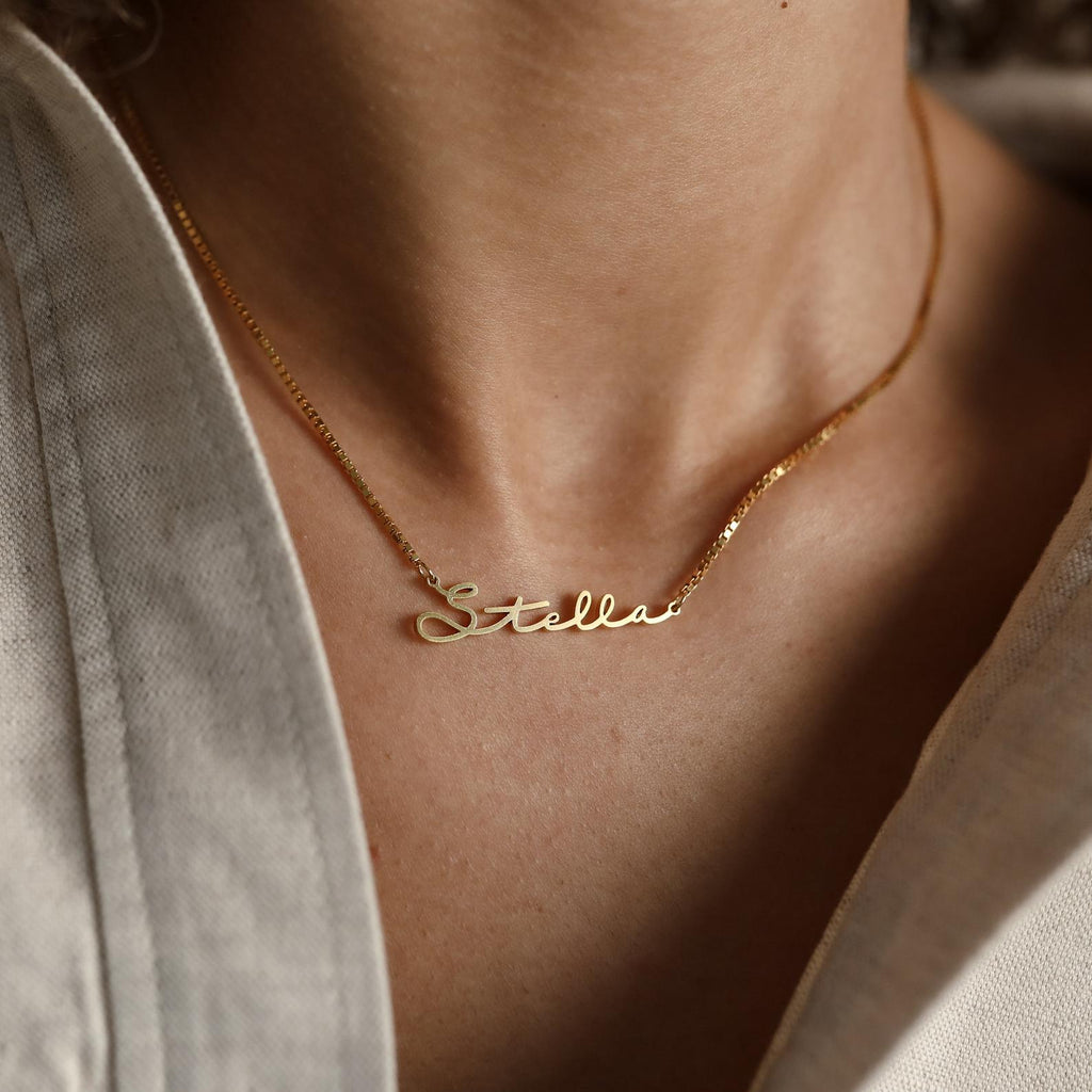 The Venice Name Necklace in Box Chain features "Stella" in elegant cursive on a delicate chain, worn gracefully around the neck.