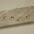 Four Zodiac Birthstone Necklaces with colorful gemstones on marble—perfect personalized jewelry or birthstone gift for any star sign.