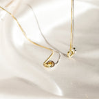 An elegant Interlocking Circles Necklace in silver and gold is displayed on smooth, ivory satin fabric.