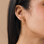 Close-up of a woman’s ear wearing Thin Hoop Earrings—stylish and simple, perfect for everyday wear—set against a neutral background.