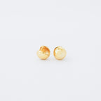 A pair of small, shiny gold Chunky Ball Hoops on a white background adds a touch of 70’s-inspired style to any look.