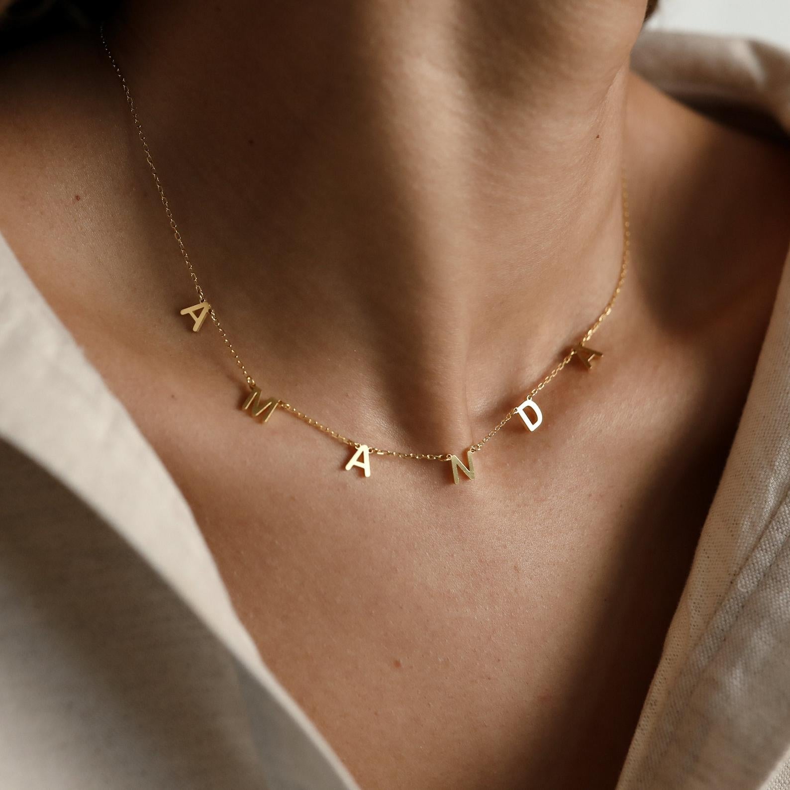 A woman wears the Alice Letter Name Necklace with charms spelling AMANDA—an elegant, personalized Christmas gift idea.
