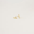 The Dainty Bar Studs in gold are perfect for a minimalist earrings look or layering in your earring stack, shown on a plain white background.