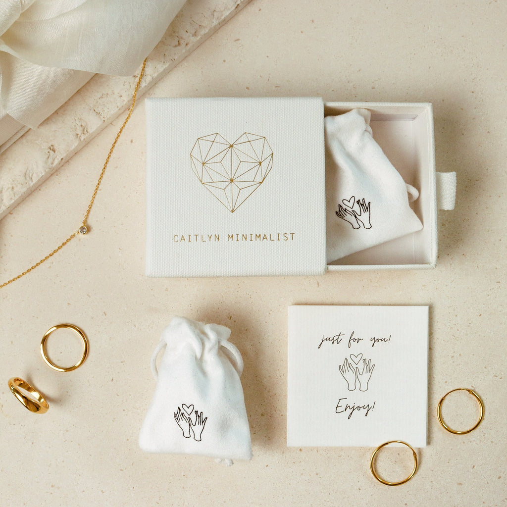 Jewelry box with rings, pouches, a necklace, Ribbed Link Hoops, and a card reading "just for you! Enjoy!" on a light surface.