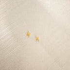 Lightning Bolt Studs in small gold rest on a textured light beige fabric background, adding a subtle yet edgy touch to any outfit.