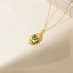 Oval Pet Necklace with an engraved cat face and the name Sam on a soft cream background—a charming personalized pet jewelry piece.