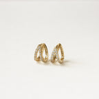 Esther Duo Pave Huggies—gold double hoop earrings with a crisscross design and sparkling crystals, reminiscent of pave huggies, shown on a plain white background.