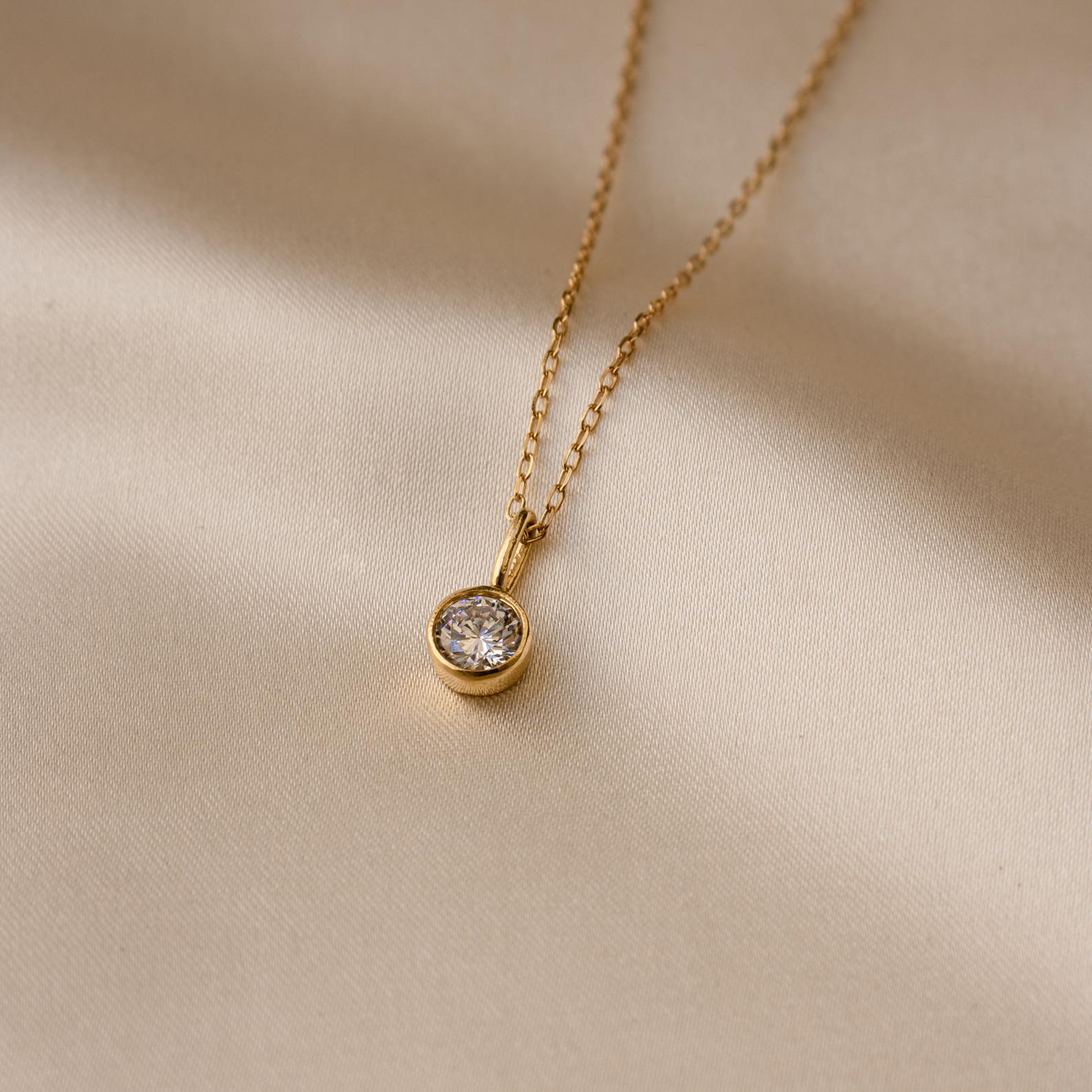 Custom Birthstone Necklace featuring a round pendant, displayed on smooth light beige fabric—an elegant and meaningful jewelry piece for any occasion.