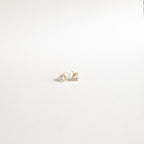Pear Diamond Studs: Minimalistic gold earrings with small, heart-shaped clear stones, elegantly showcased on a plain white background.