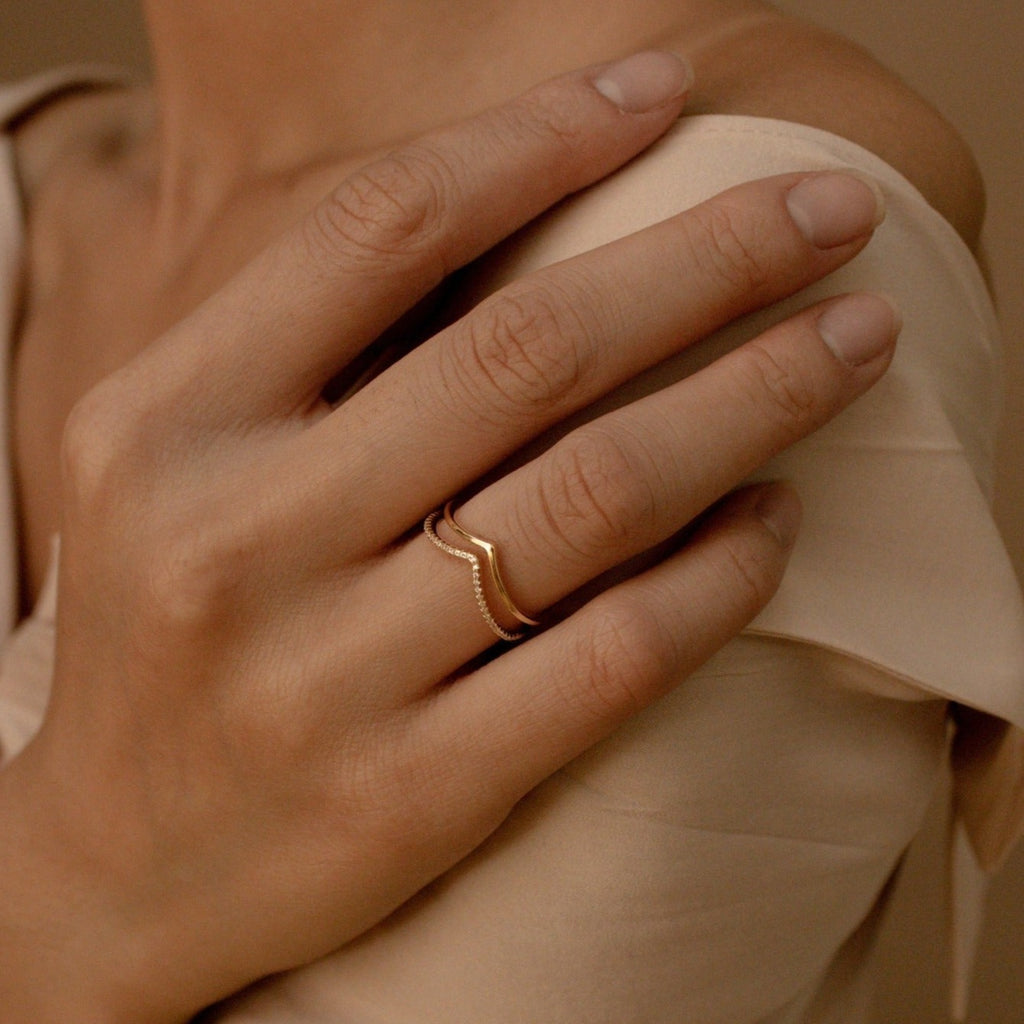 Close-up of a hand with nude nails wearing the Curve Stacking Set, touching a bare shoulder in a beige top.
