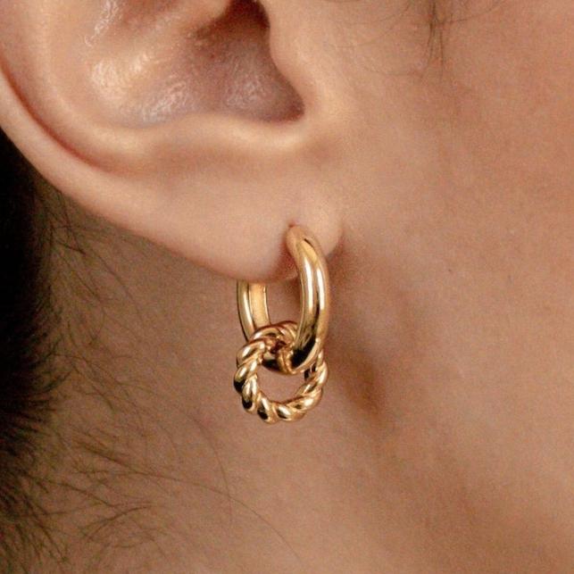 A close-up of an ear wearing Claire Duo Hoops: chunky gold earrings featuring a hoop linked with a twisted gold ring—chic and stylish jewelry.