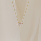 A delicate gold chain necklace featuring a small cluster of marquise-cut clear stones arranged like petals.
