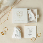The Saylor III Huggies set features minimalist gold rings, dainty hoop earrings, a necklace, and comes in a gift box with cloth pouches, displayed on a light surface.