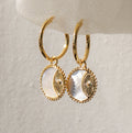 Pia Pearl Coin Hoops feature gold hoops with round white mother-of-pearl pendants and decorative gold details, adding a touch of boho elegance to any outfit.