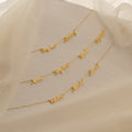 The Carrie Multiple Name Necklace is displayed on textured cream fabric with sheer beige fabric draped above.