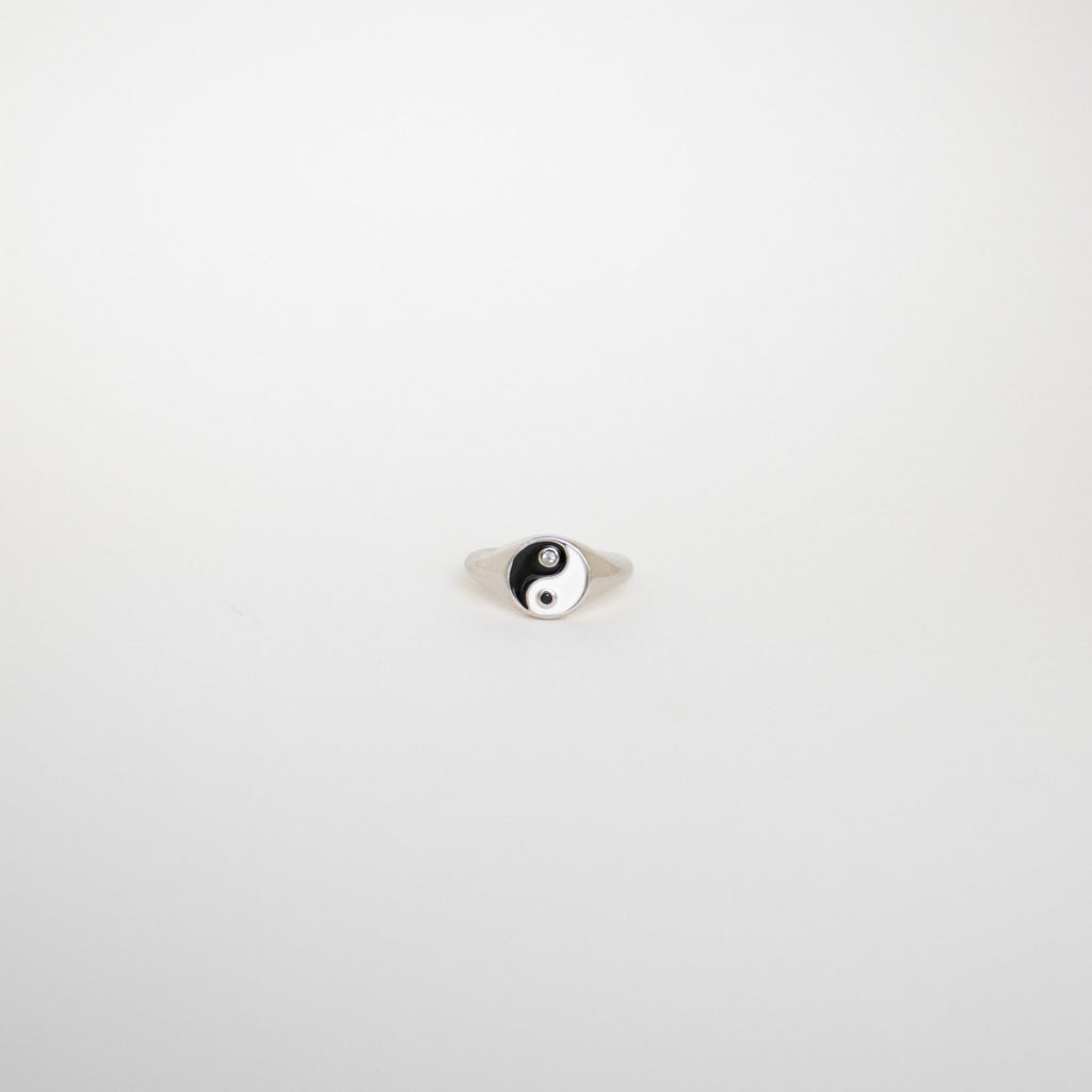The Yin Yang Ring is a silver signet ring featuring a black and white enamel yin-yang symbol, displayed on a plain white background.