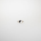 The Yin Yang Ring is a silver signet ring featuring a black and white enamel yin-yang symbol, displayed on a plain white background.