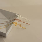 Three Flower Name Necklaces in silver, rose gold, and gold—each personalized with a name and delicate birth flowers—are displayed on a beige background.
