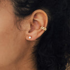 Close-up of a person's ear adorned with a gold ear cuff and Jane Diamond Studs, highlighting the sparkle of their round brilliant diamonds.