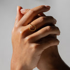Two hands clasped against a neutral background, with the Pave Open Circle Ring worn as a delicate accent on the index finger.
