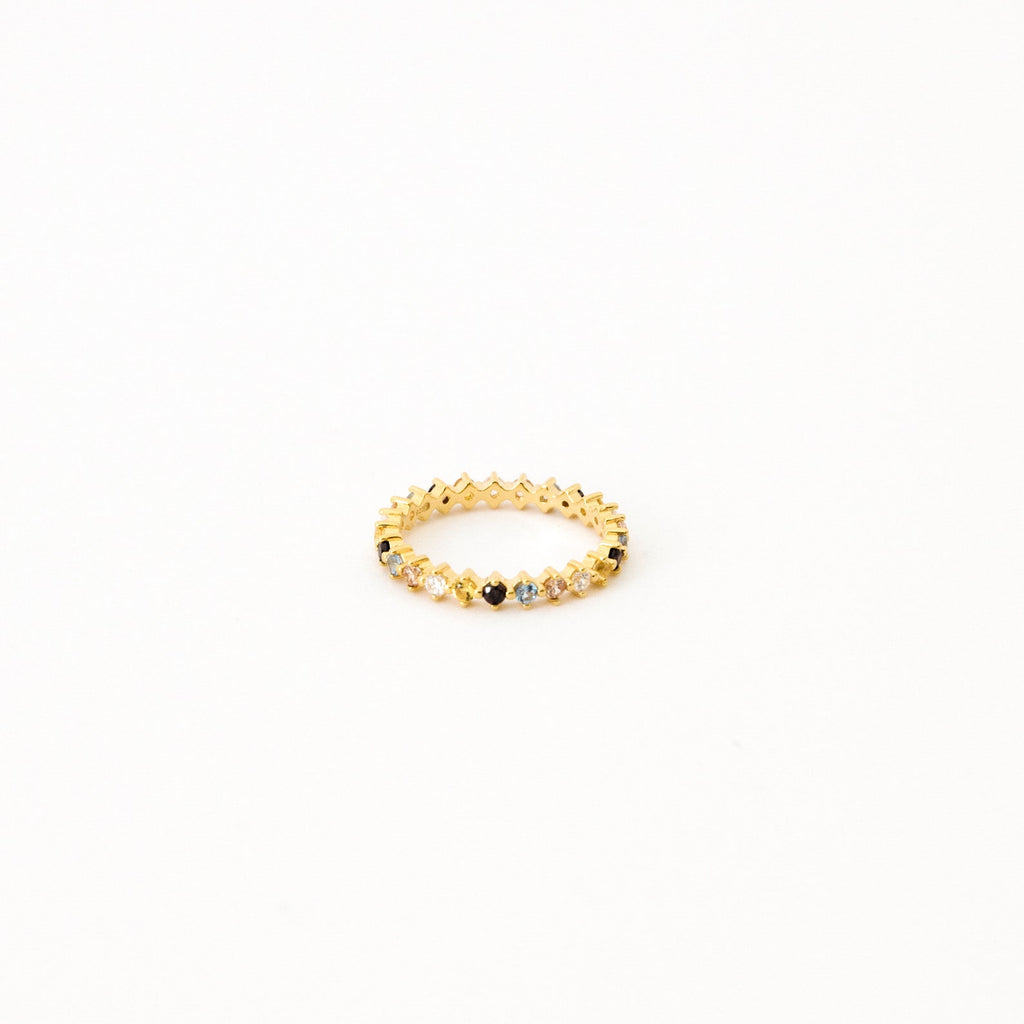 The Rainbow Crystal Ring features alternating pastel gemstones in a delicate zigzag pattern, displayed against a plain white background.