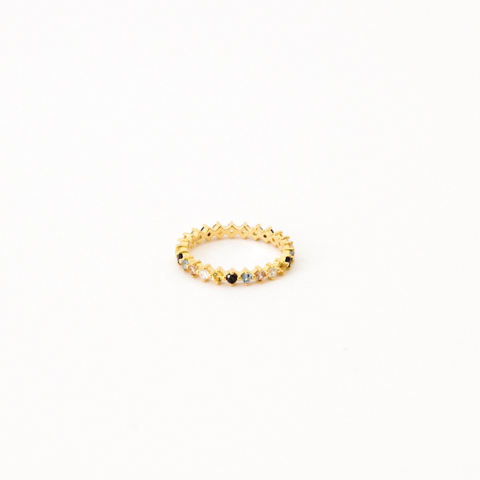 The Rainbow Crystal Ring features alternating pastel gemstones in a delicate zigzag pattern, displayed against a plain white background.