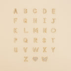 Gold and pearl letters A-Z arranged in rows, with a heart and butterfly at the bottom right—perfect inspiration for the Dangling Pave Initial Necklace, an elegant and thoughtful gift for women.