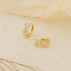 Glacier Baguette Huggies with rectangular white stones add minimalistic sparkle, shown on a light textured surface against a soft background.