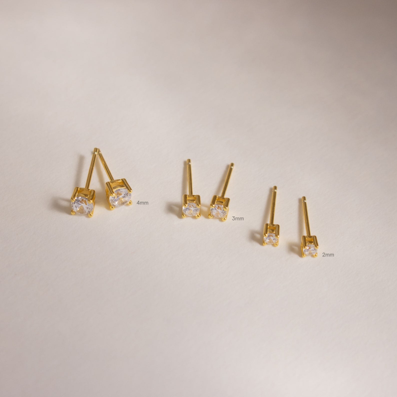 Three pairs of Booker Large Diamond Studs in gold with clear stones (4mm, 3mm, and 2mm), ideal as everyday earrings, shown on a neutral background.